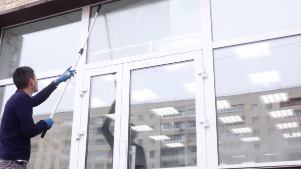 Een professionele glazenwasser zepen en piepen een raam schoon, mannelijke schoonmaakster. — Stockvideo