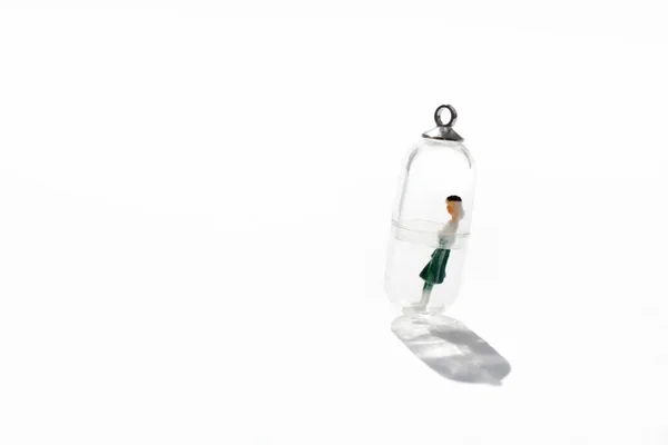 A miniature figure of a woman isolated inside a small glass capsule. Social distancing conception for stay home campaign during quarantine