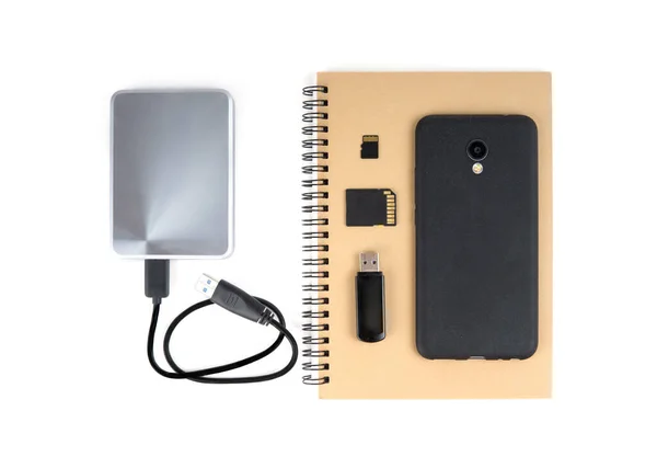 Bir dizi depolama cihazı - kağıt defter, taşınabilir sabit disk, SD kart ve cep telefonu beyaza izole edilmiş. Veri depolamanın geleneksel ve modern yolları.