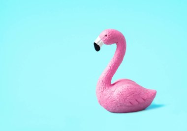 Açık mavi arka planda izole edilmiş küçük pembe bir flamingo. Yaz tatili kavramı. Düşük açı, yan görünüm.