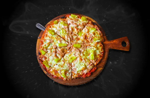 Ananas, peynir, pastırma ve tavuk malzemeli Hawaii pizzası, buhar dumanı ve siyah arka planda hareket bulanıklığı olan tuz serpiştirme..