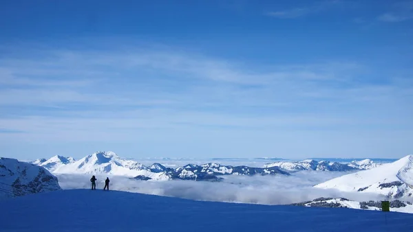 Due Sciatori Fronte Una Scogliera Fianco Della Montagna Sopra Nuvole — Foto Stock