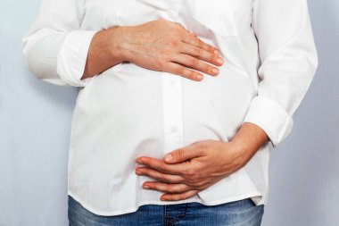 Mavi arka planda orta yaşlı hamile bir kadın..