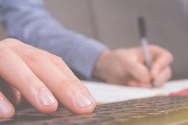 Family budget. Young businessman writing in dairy.