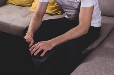 Faceless young man working on his laptop.