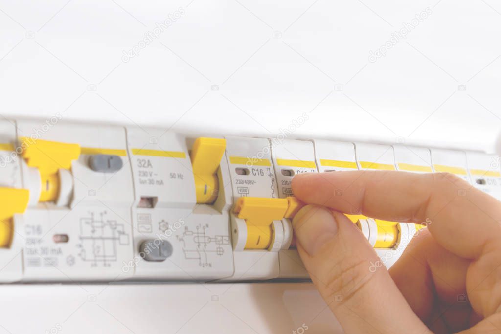 Woman hand switching on automatic fuse. Close-up.