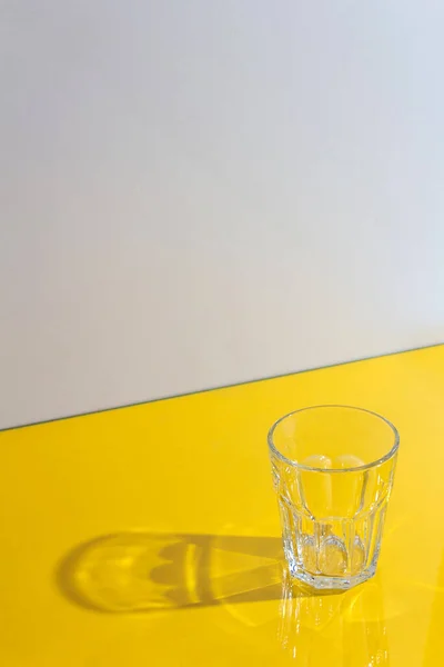 Vidrio con sombras duras sobre fondo amarillo . — Foto de Stock