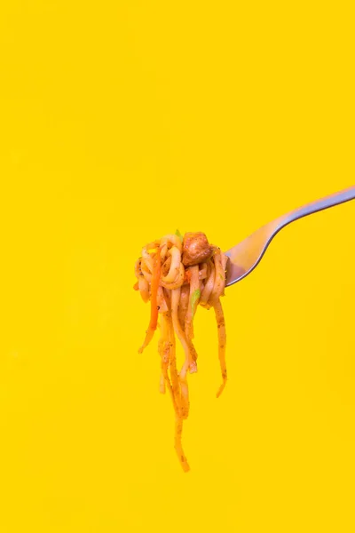 Pasta caduta dalla forchetta su fondo giallo . — Foto Stock