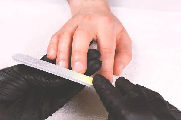 Manicura en guantes negros haciendo manicura mans. — Foto de Stock