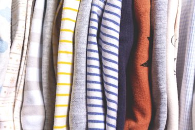 Çocukların kıyafetleri farklı. Kapatın. Çocuk kıyafetlerinin göğüs çekmecesinde dikey depolanması. Tekstil izleri. İkinci el ve kıyafet bağış geçmişi.