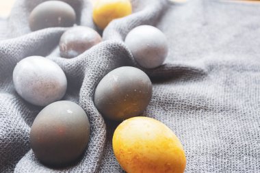 İnanılmaz boyalı Paskalya yumurtaları. Gri örgü peçete üzerinde gri mavi ve sarı yumurtalar. Evde sıcak bir Paskalya. Kapatın. Pencereden gelen güneşli ışınlar.