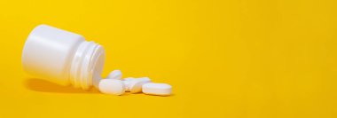 Plastik ilaç kavanozundan düşen beyaz haplar. Parlak sarı arkaplan. Sancak biçimi. Uzayı kopyala Minimalist tıp ve sağlık hizmeti konsepti. Eczacılık ilaçları, haplar. Kapat şunu..