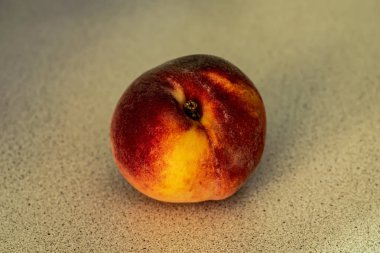 A peach on the wooden table close up