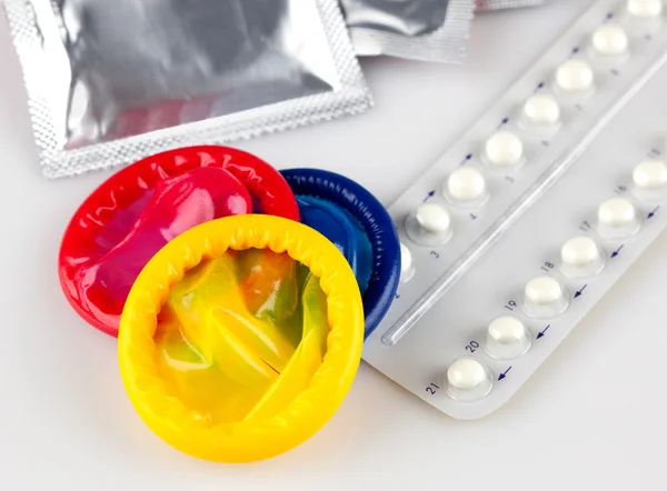 Pilules contraceptives et préservatifs, sur fond blanc — Photo