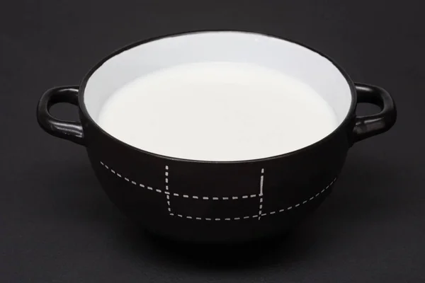 Tigela redonda preta com leite — Fotografia de Stock