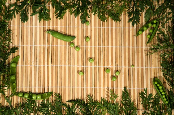 Uma armação de cenoura verde fresca com ervilhas verdes . — Fotografia de Stock