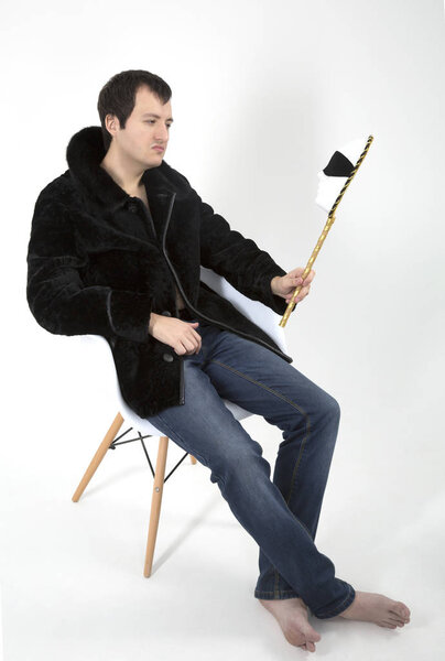 молодой человек в шубе, сидящий в белом кресле
