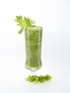 Kereviz yaprakları ve beyaz arka planda bir bardak smoothie.