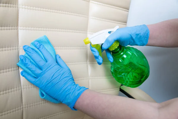 hands with rubber gloves and spray disinfected office chair