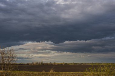Gün ortasında kahverengi alanın üzerinde kara bulutlar.
