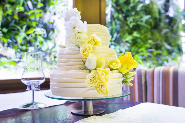 Bride\'s cake with and yellow green flowers.