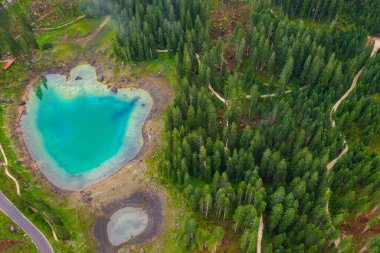 Alplerdeki Carezza Gölü 'nün turkuaz mavi sularının havadan görünüşü. Lago di Karersee köknar ağacı ormanının yanında..