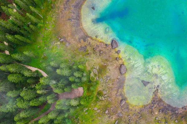 Alplerdeki Carezza Gölü 'nün turkuaz mavi sularının havadan görünüşü. Lago di Karersee köknar ağacı ormanının yanında..