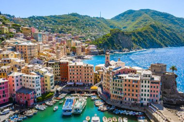 Camogli 'nin havadan görünüşü. Della Dragonara Kalesi ve Santa Maria Assunta Bazilikası Panoraması. Ligurian sahilinin yakınındaki renkli binalar. Yat ve teknelerin üzerinden limana demir atmış.