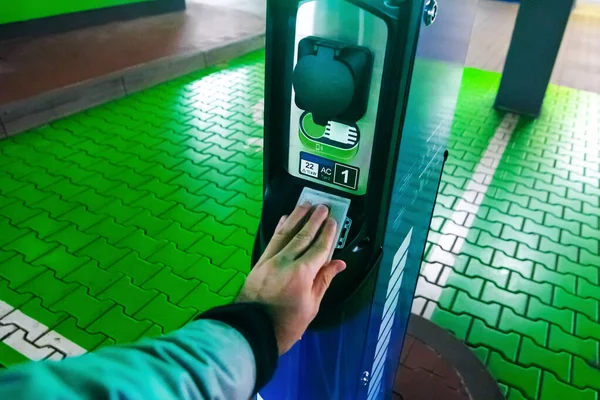 Un hombre paga por cargar un coche eléctrico. Mano sosteniendo catd para pagar en la estación de carga. Concepto de electricidad verde, medio ambiente limpio, reducción de emisiones . —  Fotos de Stock