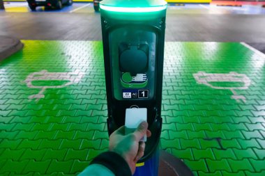Elektrikli araba için para ödeyen bir adam. Şarj istasyonunda el ele tutuşmak. Yeşil elektrik kavramı, temiz çevre, emisyon azaltımı.