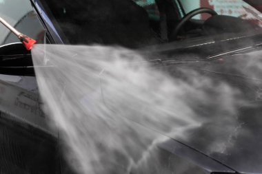 Bir adam oto yıkamada araba yıkıyor yüksek basınçlı araç yıkama makinesi suyla temizleniyor. Araba yıkama ekipmanı