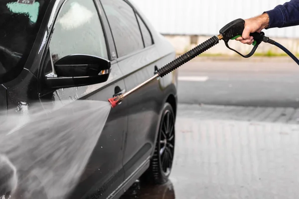 A man is washing a car at self service car wash. High pressure vehicle washer machine clean with water. Car wash equipment — Stock Photo, Image