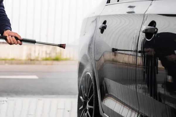 Um homem está lavando um carro em auto-serviço de lavagem de carro.Máquina de lavar veículos de alta pressão limpa com água. Equipamento de lavagem de carro — Fotografia de Stock