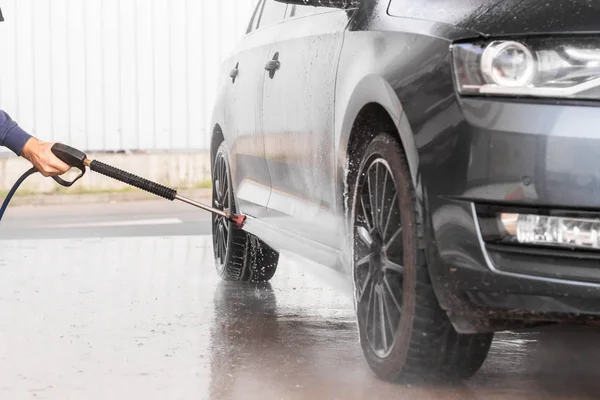 Bir adam oto yıkamada araba yıkarken yüksek basınçlı araç yıkama makinesi köpük püskürtür. Mlada Boleslav, 10.12.2019 — Stok fotoğraf