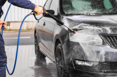 Bir adam oto yıkamada araba yıkarken yüksek basınçlı araç yıkama makinesi köpük püskürtür. Mlada Boleslav, 10.12.2019