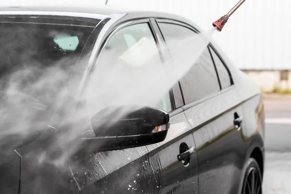 Ein mann wäscht ein auto an der autowaschanlage selbstbedienung. hochdruckfahrzeug waschmaschine mit wasser reinigen. Autowaschanlage, mlada boleslav, 10.12.2019 — Stockfoto