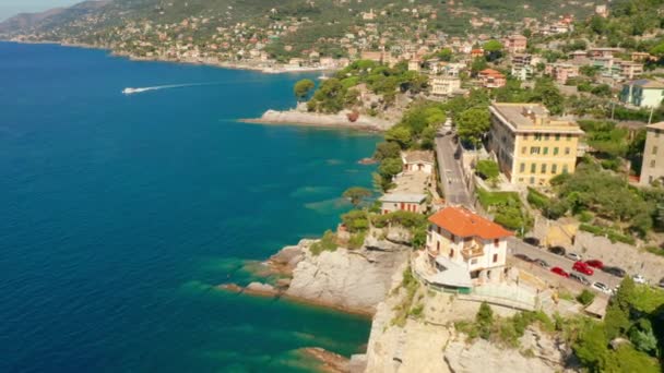 Leť nad mořem s obrovskými kameny pod tyrkysově modrou mořskou vodou. Camogli město s tradičními barevnými domy v blízkosti Janova, Itálie. — Stock video