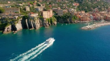İtalya 'nın Cenova kenti yakınlarındaki Camogli limanına giden küçük bir yolcu gemisi var. Kayalık sahil boyunca marinaya bir motorlu tekne geliyor..