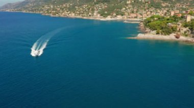 İtalya 'nın Cenova kenti yakınlarındaki Camogli limanından küçük bir yolcu gemisi denize açılıyor. Kayalık sahil boyunca marinaya bir motorlu tekne geliyor..