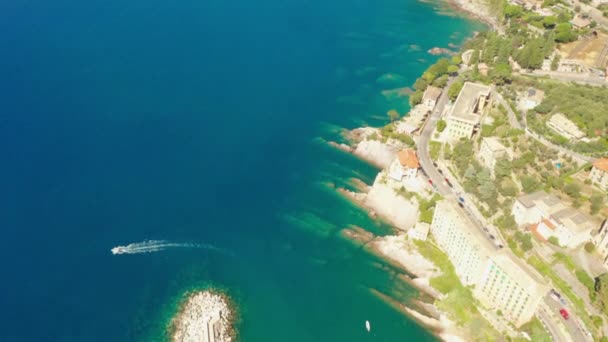 Vlieg over zee met enorme stenen onder het turquoise blauwe zeewater. Camogli stad met traditionele kleurrijke huizen in de buurt van Genua, Italië. Een kleine boot vaart vanuit de haven van de Ligurische zee — Stockvideo