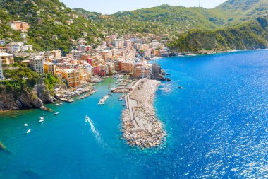 Marina and breakwater where lighthouse is located. Boat sailing to the harbor in ligurian sea, Camogli near Portofino, Italy. Aerial view on traditional Italian colorful houses