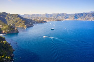 Yat ve teknelerin Arial manzarası, dağlık arka planda Liguric Denizi 'nde yelken açmak, Portofino, İtalya. Üzerinde geleneksel İtalyan evleri olan kayalar ve tepeler.