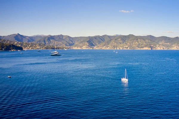 Yacht is sailing in the sea with bright blue water on the mountain background. Boat in Ligurian sea, Portofino, Italy