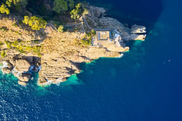 意大利波尔图菲诺港一座灯塔的顶部景观 灯塔矗立在靠近大海的岩石山上 蓝色碧绿的海水映衬着它 利古里亚的大海用大石头冲刷着海岸 — 图库照片