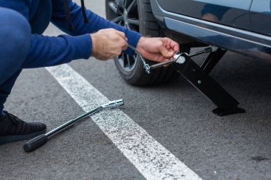 Adam bozuk araba ve tekerlek değişimi kullanıyor. Lastik değiştirme kavramı
