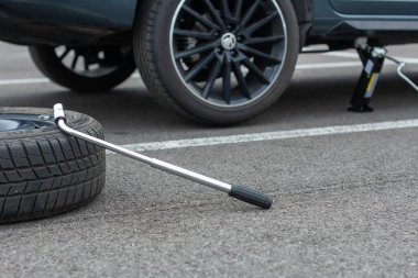 Patlak bir tekerlek ve tornavida kırık arabanın arka planında asfalt bir yolda. Jack bir araç kaldırıyor. Otomobil servisi. Lastik değiştirme konsepti, Prag, Mart 2020