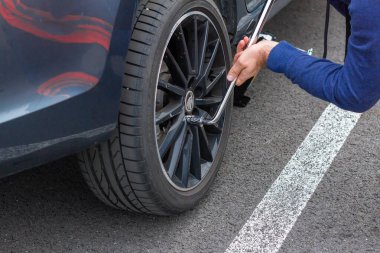 Erkek eli tornavida kullanarak tekerleği değiştiriyor. Kış ve yaz lastikleri değiştiriliyor. Mevsimlik lastik değiştirme konsepti. Hizmet süreci. Prag, Mart 2020.