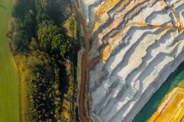 Yol boyunca uzanan bir kum ocağının en üst manzarası. Kum havuzu bir ormana yakın. Doğal kaynakların veya cevherlerin madenciliği