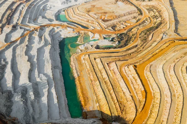 Top view on a stone quarry. Arial view on a mining of natural resources or ore. Green river separates white and yellow sand shores. Waterline with two types of a land. Natural texture