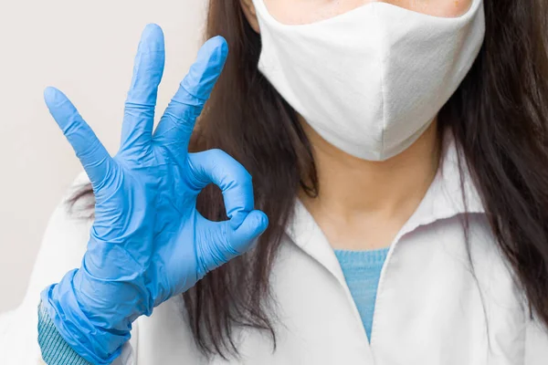 Doctor shows ok in blue gloves and protective mask in the fight with coronavirus, 2019-nCoV, SARS-Cov-2, flu. Concept of health care and good medicine